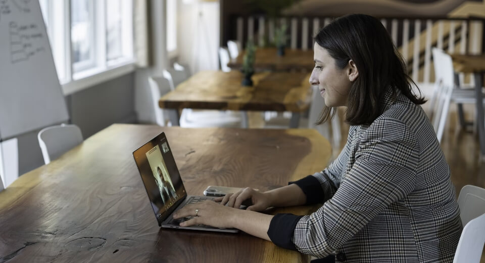 A person having at a table, attending an online meeting.
