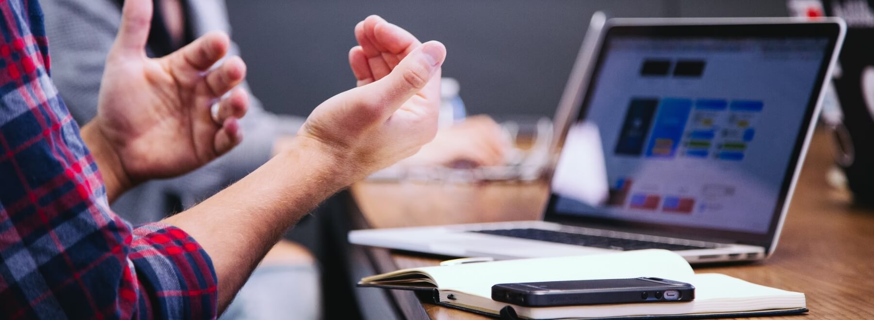 A person making hand gestures in front of a laptop.