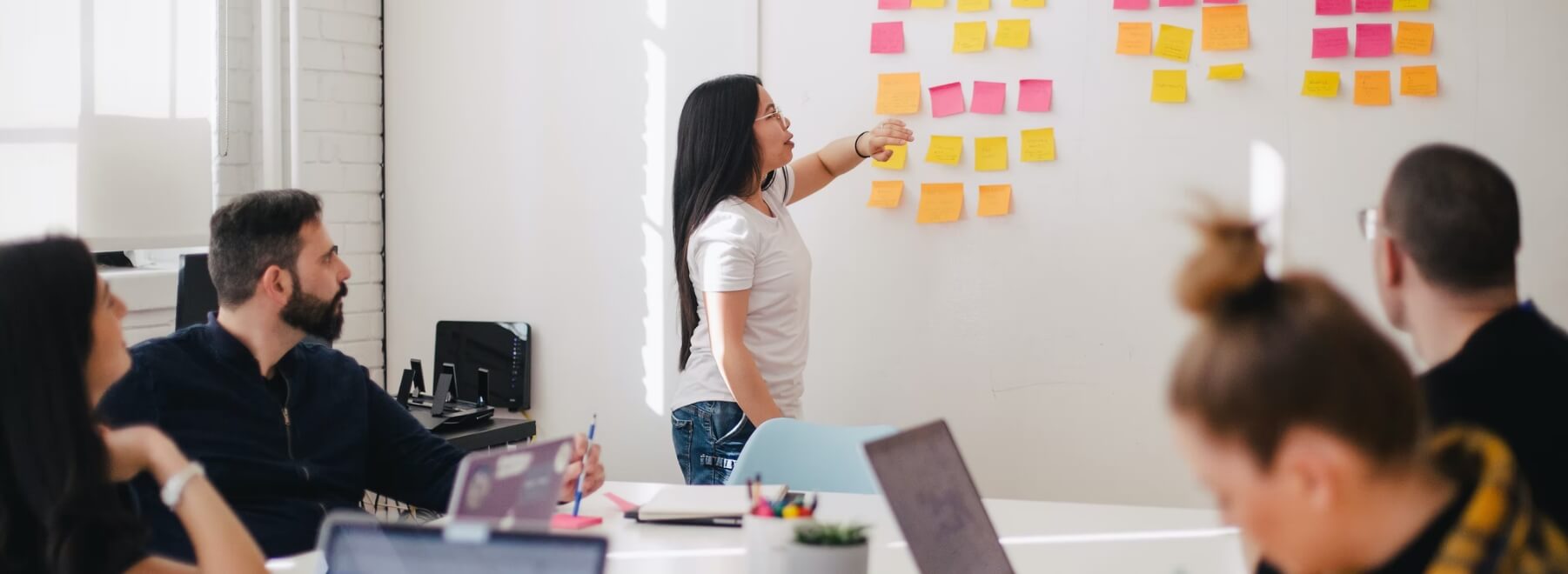 A group of people in front of a project management board.