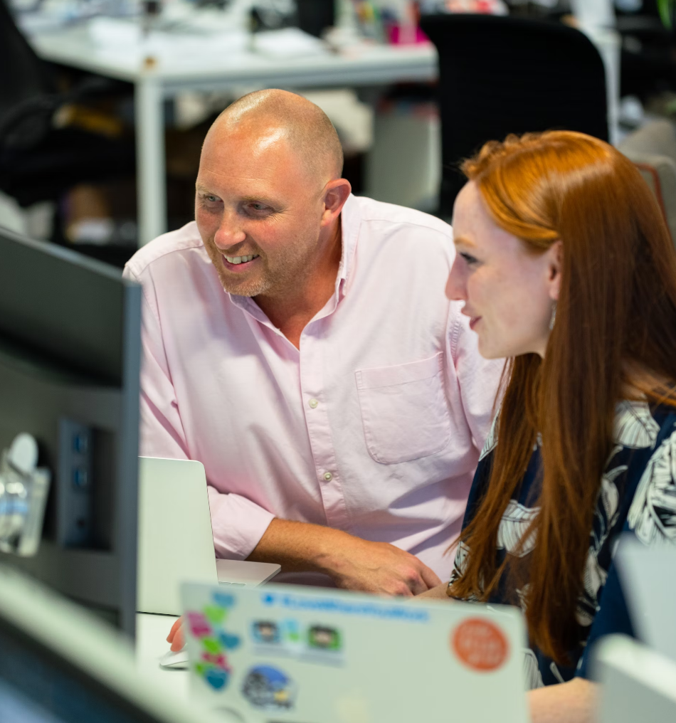 Two people in front of a computer, smiling.